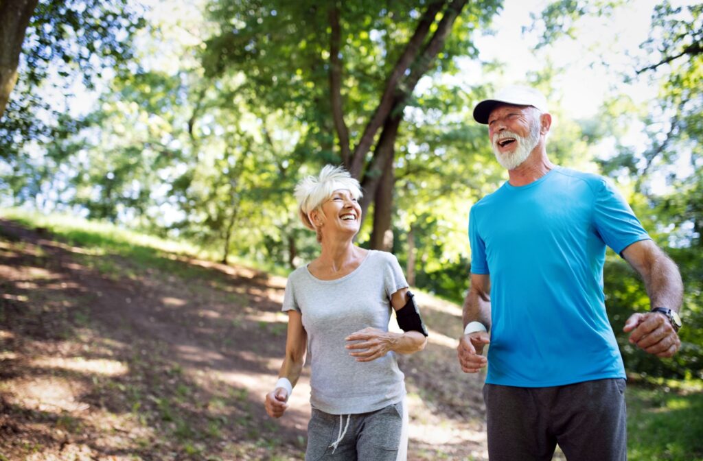 2 older adults smiling while jogging outdoors.