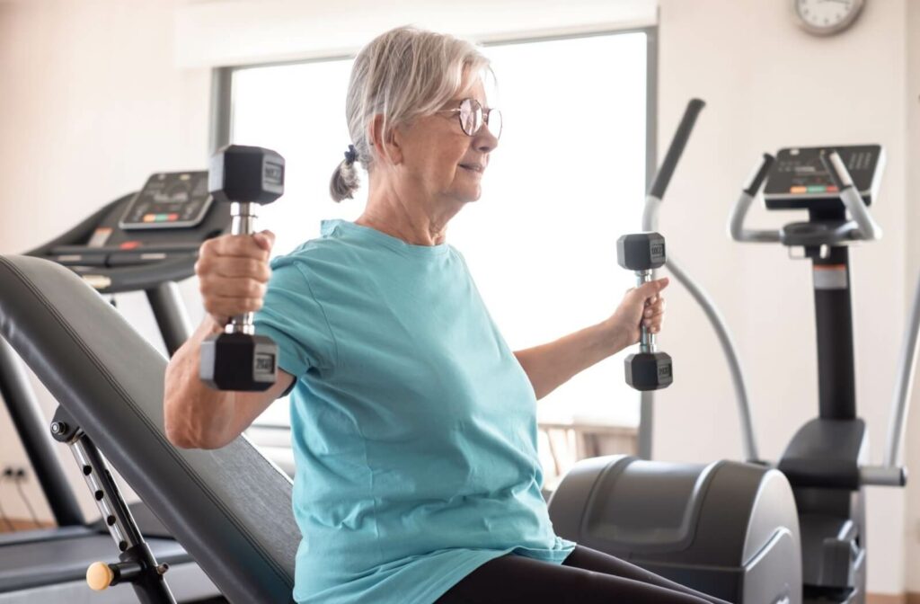 An older adult lifting weights as part of their workout routine in a fitness center at a senior living community