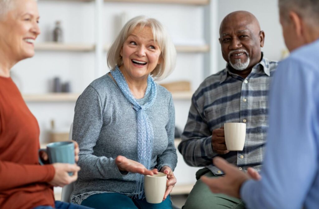 A group of friends in senior living have an animated conversation over morning cups of coffee