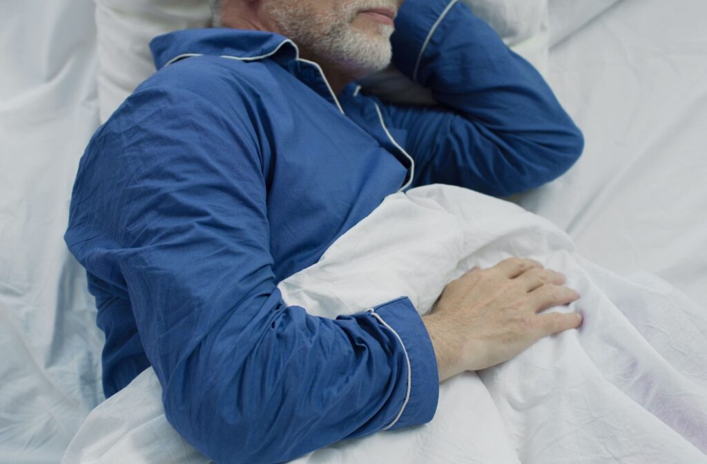 A senior is sleeping in bed with the room at an optimal temperature.