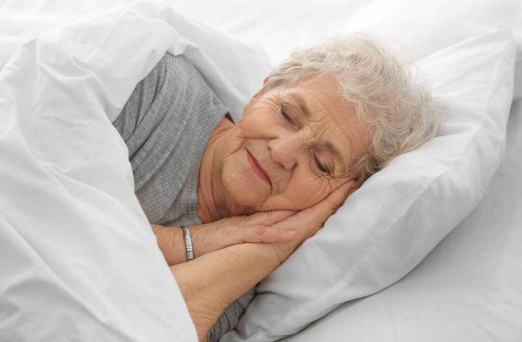 A senior is sleeping peacefully in bed.
