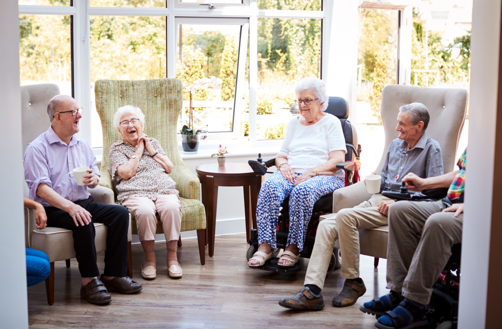 A group of happy seniors share a conversation at a senior living community.